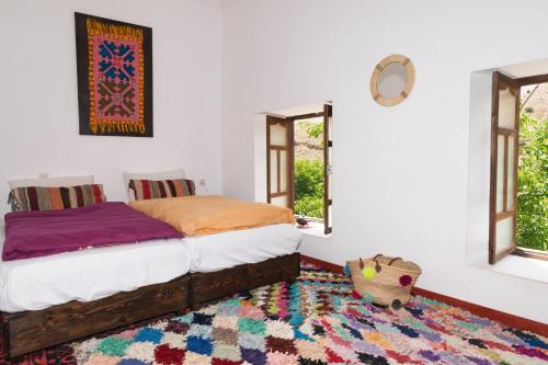 a bedroom with a bed with a rug and windows at Auberge Sremt in Sremt