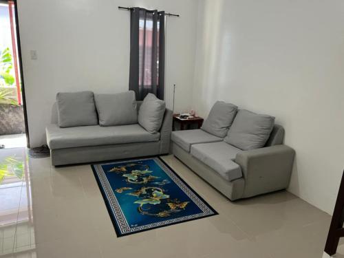 a living room with two couches and a rug at Juriz staycation Place in Santo Tomas