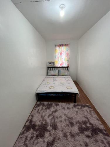 a small room with a bed and a rug at Juriz staycation Place in Santo Tomas