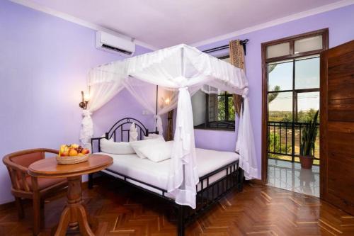 a bedroom with a canopy bed and a table at Mrimba Palm Hotel in Arusha