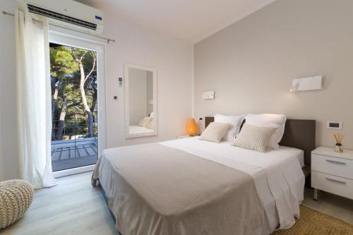a white bedroom with a large bed and a window at Magnificent Seafront Villa 10 Bedrooms Pakleni View Villa Private Infinity Pool & Amazing Sea Views Hvar Town in Hvar