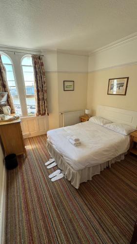 a hotel room with a large bed and two windows at New Birchfield Hotel in Weston-super-Mare