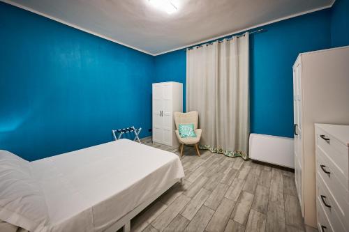 a bedroom with blue walls and a bed and a chair at La Maison Apparthotel in Praia a Mare