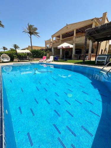 a large blue swimming pool in front of a building at فيلا اول صف بحر مارينا الساحل الشمالي العلمين برايفت بول in El Alamein