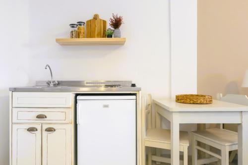 a white kitchen with a sink and a table at Scala Apartments in Kastraki Naxou