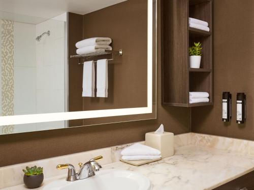 un bagno con lavandino, specchio e asciugamani di Varscona Hotel on Whyte a Edmonton