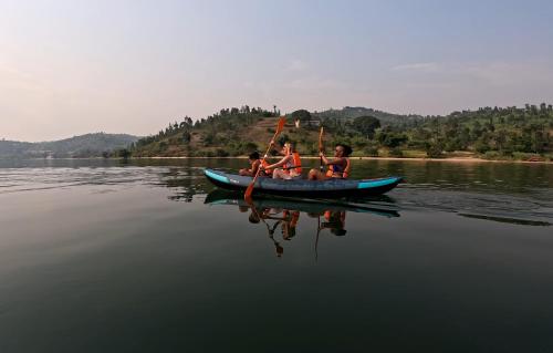 three boys are rowing a boat on a lake at Umutuzo Lodge Kivu Lake in Buhoro