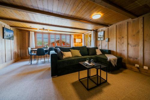 a living room with a green couch and a table at Mountain View near Brienz - free parking in Kienholz