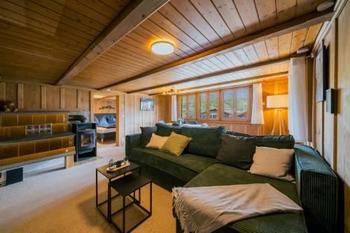 a living room with a green couch and a kitchen at Mountain View near Brienz - free parking in Kienholz
