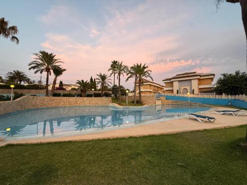 a large swimming pool with palm trees and a building at Aparthotel Bahia Pinosol in Jávea