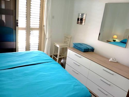 a bedroom with a blue bed and a mirror at Sunset Apartment in Peyia