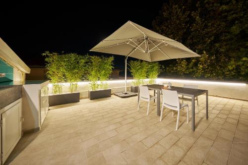 a table and chairs with an umbrella on a patio at La Maison Apparthotel in Praia a Mare