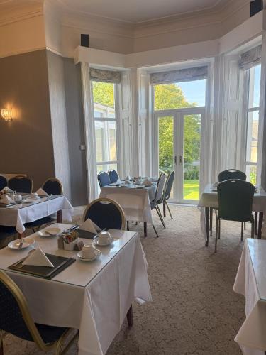 a dining room with tables and chairs and windows at Chase Hotel in Whitehaven