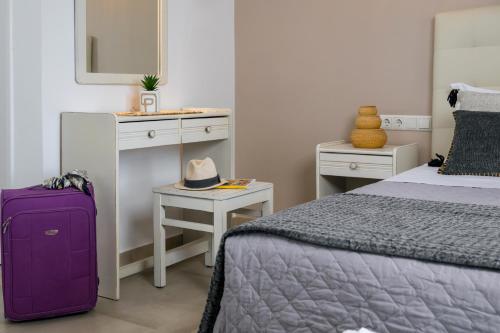 a bedroom with a purple suitcase next to a bed at Scala Apartments in Kastraki Naxou