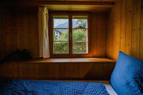 a bedroom with a window and a bed with a blue blanket at Mountain View near Brienz - free parking in Kienholz