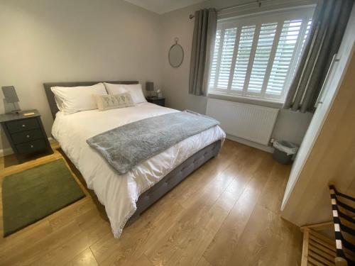 a bedroom with a large bed with a wooden floor at Sun Terrace Lodge Weybridge in Oatlands Park