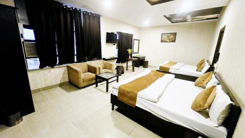 a hotel room with two beds and a couch at Hotel HK Continental in Amritsar