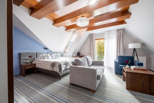 a bedroom with a bed and a couch and a chair at Hotel Willa Pod Skocznią in Zakopane
