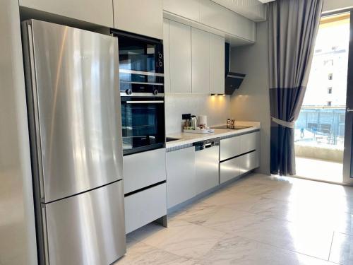 a kitchen with white cabinets and a stainless steel refrigerator at Via Mar Residence - Alanya Experience in Alanya