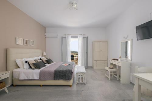 a white bedroom with a bed and a television at Scala Apartments in Kastraki Naxou