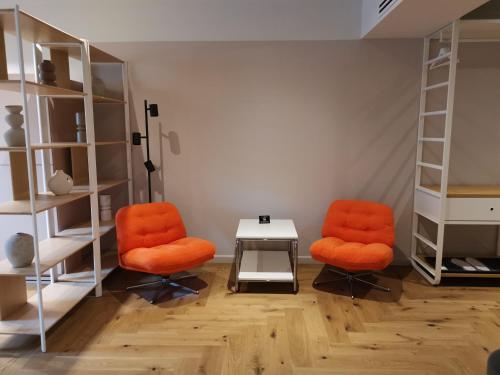 two orange chairs and a table in a room at Atlas Aparthotel in Piatra Neamţ