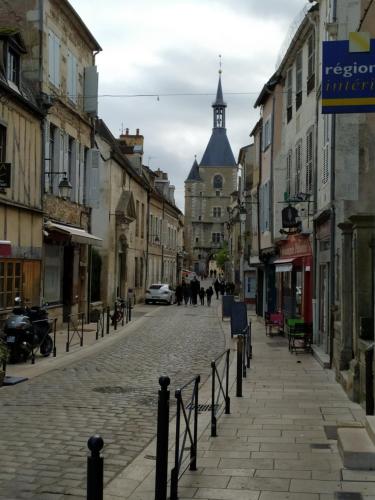 a cobblestone street in an old town with a clock tower at Presbytère in Marigny-sur-Yonne