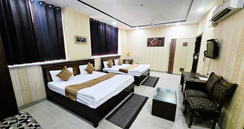 a hotel room with two beds and a television at Hotel HK Continental in Amritsar