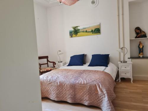 a bedroom with a large bed with blue pillows at Presbytère in Marigny-sur-Yonne