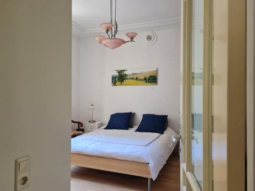 a bedroom with a bed with blue pillows and a chandelier at Presbytère in Marigny-sur-Yonne