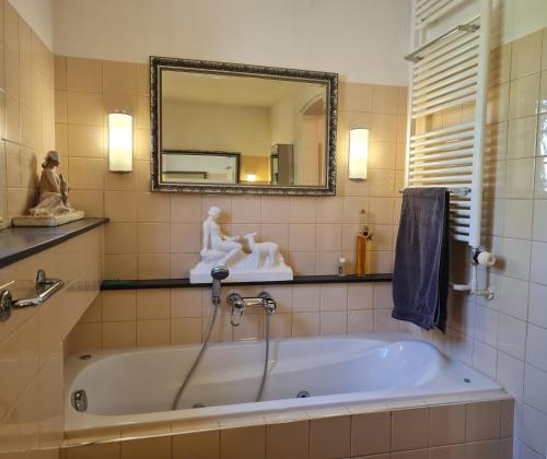 a bath tub in a bathroom with a mirror and statues at Presbytère in Marigny-sur-Yonne