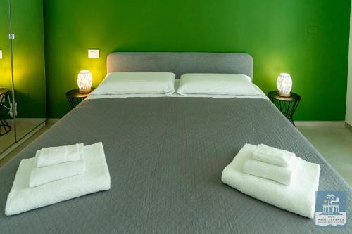 a large bed with two white towels on it at Villa Mediterranea Apartments - Seaview, Pool & Garden in Bari