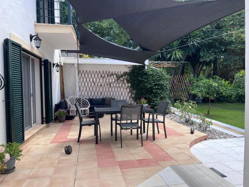a patio with a table and chairs under a black umbrella at Casa NB in Gouvia