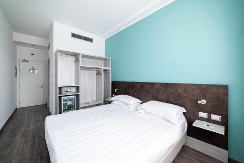 a bedroom with a large bed with white sheets at Phi Hotel Milano in Baranzate