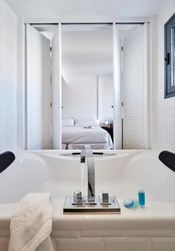a white bathroom with a tub and a bedroom at Delamar 4*Sup-Adults only (18+) in Lloret de Mar