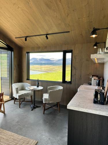 a kitchen with a table and chairs and a large window at Hvammsvík Nature Resort in Kjósahreppur