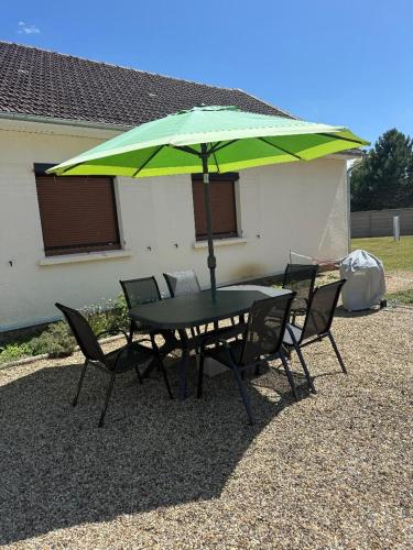 a table and chairs with a green umbrella at Maison cosy à Moyvillers classée de tourisme 3 étoiles in Moyvillers