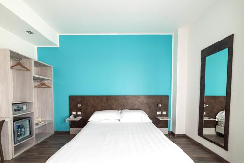 a bedroom with a large bed and a blue wall at Phi Hotel Milano in Baranzate