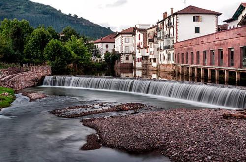 a waterfall in the middle of a river with buildings at Apartamento Larrazu II Agroturismo Baztán in Arráyoz