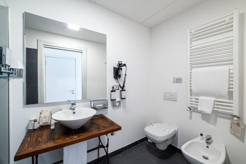 a bathroom with a sink and a toilet and a mirror at Phi Hotel Milano in Baranzate