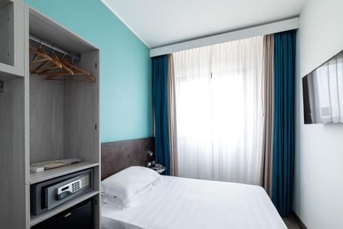 a bedroom with a bed and a tv and a window at Phi Hotel Milano in Baranzate