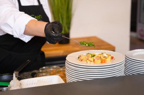 a person holding a spoon with a plate of food at Green Garden Hotel in Raszyn