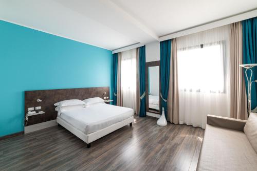 a bedroom with a white bed and a blue wall at Phi Hotel Milano in Baranzate