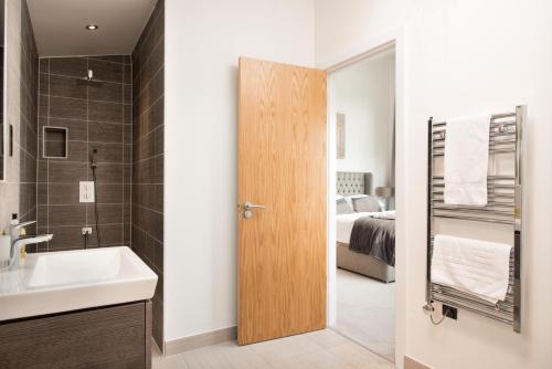 een badkamer met een wastafel en een badkamer met een bed bij The Cotswolds Manor ML26 Lower Mill Estate. in Somerford Keynes