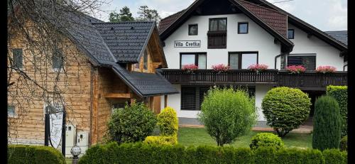 a white house with pink flowers on a balcony at Apartments Vila Cvetka Bled in Bled