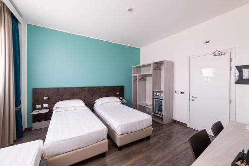 two beds in a room with blue walls at Phi Hotel Milano in Baranzate