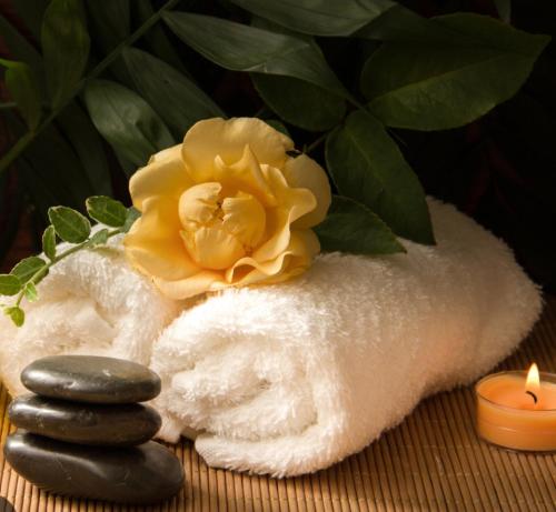 a towel with two stones and a flower and a candle at Borbon Home luxury rooms & SPA in Palermo