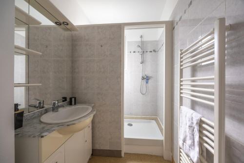 a white bathroom with a sink and a shower at Le Bassin in Port-en-Bessin-Huppain