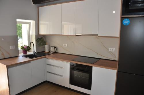 a kitchen with white cabinets and a black refrigerator at Angelina in Jakišnica