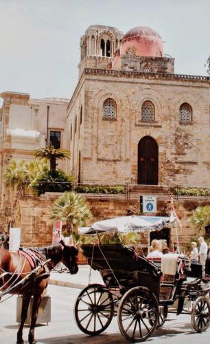 a horse drawn carriage in front of a building at Borbon Home luxury rooms & SPA in Palermo