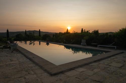 a swimming pool with the sunset in the background at Le Sorbelle D'Orcia in Pienza